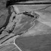 Oblique aerial view centred on the cropmarks of the enclosures and field system with the farmhouse and chapel adjacent at Chapeltown, looking to the SW.