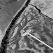 Oblique aerial view centred on the cropmarks of the round barrows, unenclosed settlement, souterrains, pits and rig at Auchenreoch, looking to the E.