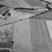Oblique aerial view centred on the cropmarks of the enclosed settlement, ditch defined cursus, enclosure, ring ditches, barrows, pits and rig with the farmstead adjacent, looking to the NW.