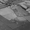 Oblique aerial view centred on the cropmarks of the circular enclosure, possible soutterain, field boundaries, pits and rig at Mains of Haulkerton with Laurencekirk adjacent, looking to the SSE.