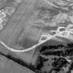 Oblique aerial view centred on the cropmarks of the enclosure and the former airfield at Brackla House, looking to the W.