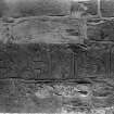 View of visible side face of recumbent grave-slab, (St Vigeans no.8), set in wall of St Vigeans Church, prior to removal.