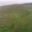 Skipisdale, Mingulay, oblique aerial view centred on the remains of the roundhouse, buildings, field banks and lazy beds, with the settlement mound adjacent and a peat stack stand in the foreground, taken from the E.