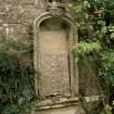 Detail of niche in wall of formal garden with carved head above and stone fragment inside.
