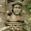 Detail of carved head above niche in wall of formal garden.