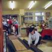 'Loch Doon' logboat experimental reconstruction (at Scottish Fisheries Museum, Anstruther): spring 1992. Launch day: Dr R Prescott lays protective planking through museum shop.
