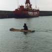 'Loch Doon' logboat experimental reconstruction (at Scottish Fisheries Museum, Anstruther): spring 1992. Launch day: logboat in water, with Mark Lawrence paddling.
(North Carr light vessel in background).
