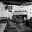 Tiree, Kilmoluag, interior.
View of kitchen with occupant Mr MacKinnon seated in chair.