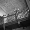 Edinburgh, Niddrie Marischal House, interior.
General view of the staircase balcony, showing the lamp fittings on the gallery rail and the ornate ceiling.