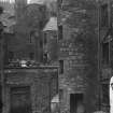 View of North West corner of St John Street, Edinburgh, with children sitting on the roof. This area was covered in after 1877 and before 1894. This area is now an open courtyard. Also showing Smollett's Lodging (right).