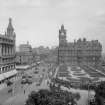 View looking east from Scott Monument towards Calton Hill showing the North British Hotel and Waverley Gardens and a busy Princes Street with shop awnings, trams, cars and pedestrians.