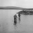 View of RCAHMS surveyors wading out to a dun in 1924, Dun Nighean Righ Lochlainn, North Uist. Research indicates that they inlcude G P H Watson (middle) with a local ghillie on the right.
