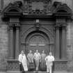 Detail of Chapel doorway within the Quadrangle, shown with domestic staff.