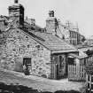 General view of Jeanie Dean's Cottage on edge of Holyrood Park, showing part of St Leonard's Bank behind, and with woman sitting on window ledge of cottage.