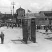 View from WSW of factory entrance main gate (E) with an air-raid shelter and Bishopton station in the background.