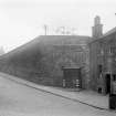 View of the Flodden Wall on Drummond Street seen from the Pleasance from the East. The South facade of No. 31a Pleasance can be seen along with a Police Box.
