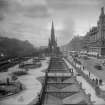 General view along Princes Street with Scott Monument in centre, also showing trams, awnings on shop fronts and horse and carriages
