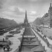 General view along Princes Street with Scott Monument in centre, also showing trams, awnings on shop fronts and horses and carriages