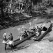 Group seated in two ferry canoes moored in stream.  Unknown location.