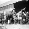 Group loading a cart with packing crates outside a warehouse.  Unknown location, probably at Howrah Station, Kolkata.