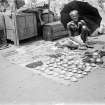 Street vendor selling bowls and necklaces.  Unknown location.