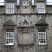 View of E side of courtyard, showing relief carvings of the Evangelists Mark (left) and Luke (right) in pediments above upper windows; inscription panel between lower windows; and a sundial between upper windows.