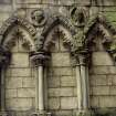 View of two carved medallion heads, between ground floor arches on S side of tower on W facade of Holyrood Abbey.
