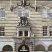 View of facade of building, showing Church of Scotland coat of arms above entrance, cherubs above second floor windows, and rams' heads below fourth floor windows.