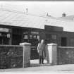 Scanned copy of a slide of J Y Dick, bootmaker outside his workshop in Dalhousie Road,  Newtongrange. Lent for copying by the Gorebridge and District Local History Society.