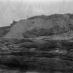 Excavation photograph: Spoil dumped over cliff, entrance to house 1 visible above.