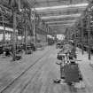 Interior view of North British Engine Works, 739 South Street, Glasgow, from North-East showing Bay 'B', upper floor level, main workshop. View shows on left side of railway line a group of capstan and turret lathes. In the centre aisle are several centre lathes which each have their own electric drive motor. (An unusual feature for the date of the factory, c. 1915; most machine tools of the period were belt driven from line shafts.) On the right hand side, and only partly shown is a Norton cylindrical grinder, a group of centre lathes, behind which is a group of heavy production pillar drills. Note the line shafts and electric drive motors.