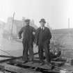 General view of the engineer and foreman for the reconstruction of Number 4 gas holder standing beside uninflated gas holder in 1933, Meadow Flat Gas Holder, Holyrood Road, Edinburgh, in 1933.