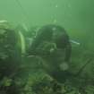 Keith Muckelroy using the water-dredge to clear debris from around one of the ship's guns. His air-line is clearly visible, and tape and drawing-board are readily to hand.