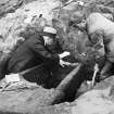 View of two gentlemen excavating a cist. The man on the right is probably Ludovic Mann.