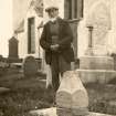 Photograph of John Nicolson standing beside an example of one of his sulptured gravestones.