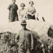 Photograph of three females kneeling on top of a haystack with a male standing in front below