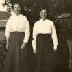 Scanned image of photograph of two females standing in front of shed