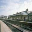 View from NW of S-bound platform, station offices and awning, with footbridge beyond