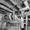 Interior. ground floor of mill, view from NE of part of a long of over-head line-shafts and pulleys taking power from the water wheel to various machines throughout the mill