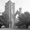 View of bell tower with clock and remains of tracery window from SW