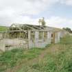 View from SE of a surviving hut showing timber framing used in construction and recent use as animal pens.