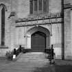 View of entrance including doorway, stained glass window above and steps.