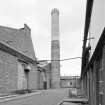 View from S of E gable of boiler house, and of circular-section brick-built boiler-house chimney