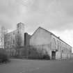 View from NW of frontage of former stationery warehouse, fronting onto Forneuk Street, with former cotton mill partially visible (left).  An addition to the N end of the mill (built in 1914) is also visible
