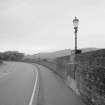 View from S showing typical lamp standard, parapet, and tarmac deck