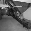 Alloa, Whins Road, Brewery, Barns Block, first floor, interior
View of bottom of the four 5 tonne malt bins dating from 1950s with automatic rotary valves installed in 1994 (these give measured amounts of grain). These bins hold chocolate and crystal malts which are measured. These are then mixed in malt bin 'E' with bulk grain and carried by conveyors to the mill room for milling. All the systems are incorporated into an automatic controlled Redler conveyor and elevator system