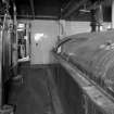 Alloa, Whins Road, Brewery, Brewhouse, mezzanine floor, interior
View showing heat exchanger (left), chilled liquor (water) tank right. First floor mill room area beyond. Here, the heat exchanger chills liquor (town water supply) to two degrees centigrade which is then used for heat transfer in the paraflow room (to cool the wort prior to entering fermentation). The recycled water is pumped into the chilled liquor vessel.