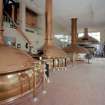 Alloa, Whins Road, Brewery, Brewhouse, first floor, interior
View showing brewhouse from W with its four traditional copper vessels. Mash tuns 1 and 2 are nearest the camera, the boiling copper (capacity of 220 barrels, which is a 'brew') and the lauter tun (19 feet 8 inches in diameter, 19 tons when empty, 45 tone when full) are visible. Hot liquor is run into mash tun no. 1 and some of this is pumped up into the copper tube carrying the malt mix from grist case no. 1. The liquor and partially mixed malt and liquor is mixed (with paddles) and heated to a pre-determined temperature for a pre-determined time before the resultant wort is pumped into the lauter tun and thence to the copper. Mash tun no. 2 (until 1980s a Decoction vessel or secondary mash vessel) was latterly used to heat liquor for the sparging process. The last mash took place on 19th/20th April 1999 but the brewhouse was re-commissioned for a mash which took place on 14th December 1999 when the Caledonian Brewery was damaged in a fire. The brewhouse coppers were installed in 1955 and were made by Christian Berner of Gothenburg, Sweden