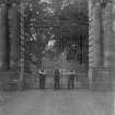 View of three men in front of Hopetoun House entrance gates with heraldic design and the date 1893