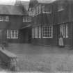 View of Skirling House courtyard with wrought iron work details and a woman standing outside